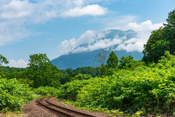 Hakodate main line railroad at Town Niseko in springtime sunny day with Mount Yotei in the background. Shiribeshi Subprefecture, Hokkaido, Japan