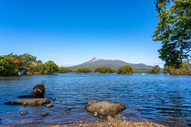 Güneşli bir günde Onuma Gölü 'nden manzara. Hokkaido Koma-ga-take ve arka planda açık mavi gökyüzü. Onuma Quasi Ulusal Parkı. Nanae Kasabası, Oshima Bölgesi, Hokkaido, Japonya