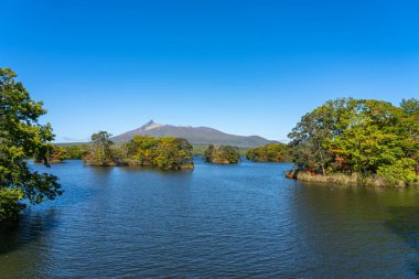 Güneşli bir günde Onuma Gölü 'nden manzara. Hokkaido Koma-ga-take ve arka planda açık mavi gökyüzü. Onuma Quasi Ulusal Parkı. Nanae Kasabası, Oshima Bölgesi, Hokkaido, Japonya