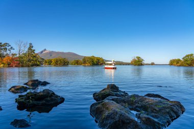 Güneşli bir günde Onuma Gölü 'nden manzara. Hokkaido Koma-ga-take ve arka planda açık mavi gökyüzü. Onuma Quasi Ulusal Parkı. Nanae Kasabası, Oshima Bölgesi, Hokkaido, Japonya