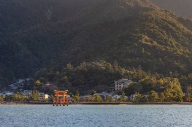 Feribottan Miyajima adasına bakıyorum. Yüzen kırmızı dev Grand O-Torii kapısı, güneşli bir günde dalgaların çekildiği körfez sahilinde duruyor, Hiroşima Şehri, Hiroşima Bölgesi, Japonya