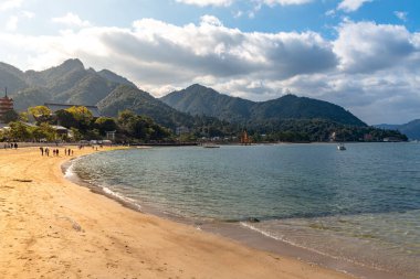 Yüzen kırmızı dev Grand O-Torii kapısı güneşli bir günde Miyajima adasının körfez sahilinde duruyor. Hiroşima 'daki Itsukushima Tapınağı' nda Yeni Yıl Hatsumode 'u. Hiroşima Bölgesi, Japonya