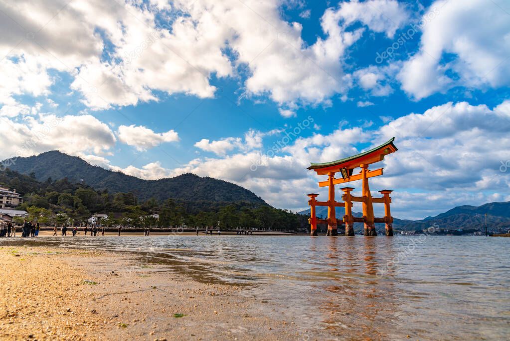 Close-up Floating orange red giant Grand O-Torii gate stands in Miyajima island bay beach at low tide on sunny day. Hiroshima City. The Three Views of Japan. Translation on gate : Itsukushima Shrine
