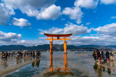Hiroşima Bölgesi, Japonya - JAN 02 2019: Güneşli bir günde Miyajima adası körfez sahilinde yüzen kırmızı dev Grand O-Torii kapısı duruyor. Itsukushima Tapınağı, Hiroşima 'da Yeni Yıl Hatsumode