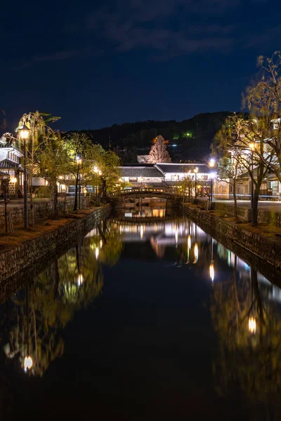 Okayama, Giappone - 27 dicembre 2019: Kurashiki Bikan Historical Quarter si illumina di notte. Paesaggio urbano noto per le tipiche pareti bianche giapponesi di residenze e salici che costeggiano le rive del fiume — Foto Stock