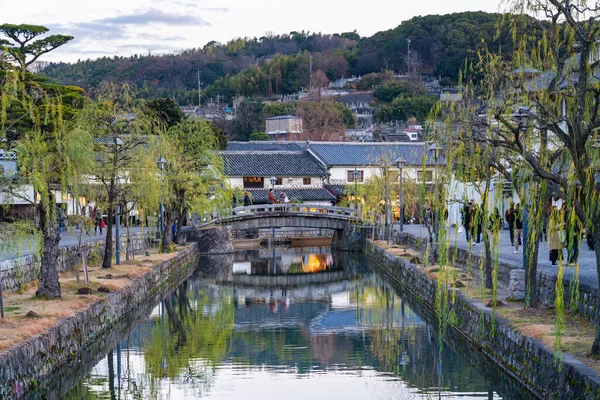 Okayama Bölgesi, Japonya - 27 Aralık 2019: Kurashiki Bikan Tarihi Bölgesi, alacakaranlıkta. Kentin tipik Japon yerleşim yerlerinin beyaz duvarları ve nehir kıyısında söğüt ağaçlarıyla bilinen manzarası. — Stok fotoğraf