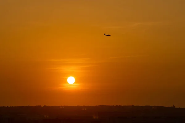 Sole che tramonta con una silhouette di aeroplano in sfondo cielo colorato — Foto Stock