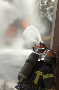 Araba yanıyor alev ve iki itfaiye tugay kask ile yakmak 