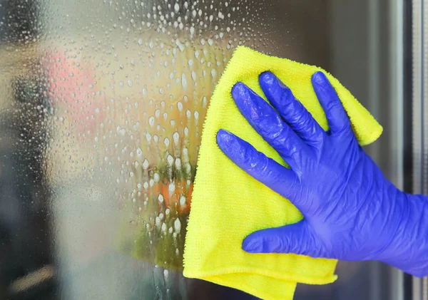 Mujer limpiando una ventana con un paño amarillo — Foto de Stock