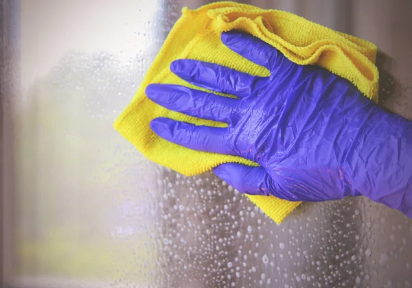 Mujer limpiando una ventana con un paño amarillo — Foto de Stock