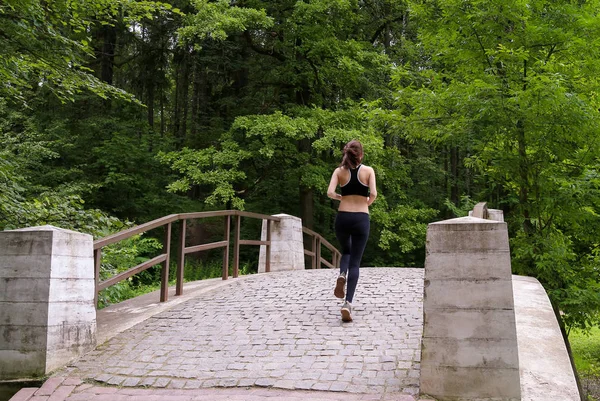 Young woman runs on a stone bridge