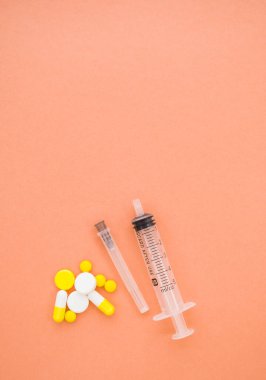 İçinde iğne, farklı haplar ve turuncu arka planda haplar olan bir şırınga. Coronavirus kavramını durdur. Kendini koru..