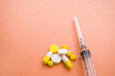 İçinde iğne, farklı haplar ve turuncu arka planda haplar olan bir şırınga. Coronavirus kavramını durdur. Kendini koru..
