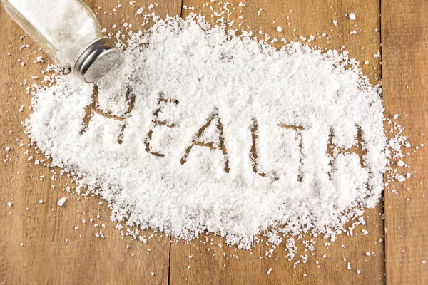 Glass salt shaker  on wooden and health word on salt — Stock Photo, Image