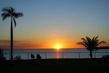 Couple watching the sunset over sea from their relaxing chairs. clipart