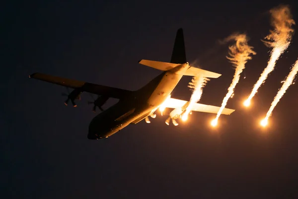Military plane firing flares during a  night flight — Stock Photo, Image