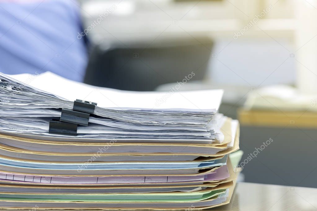 Stack of documents in files on desk in office.