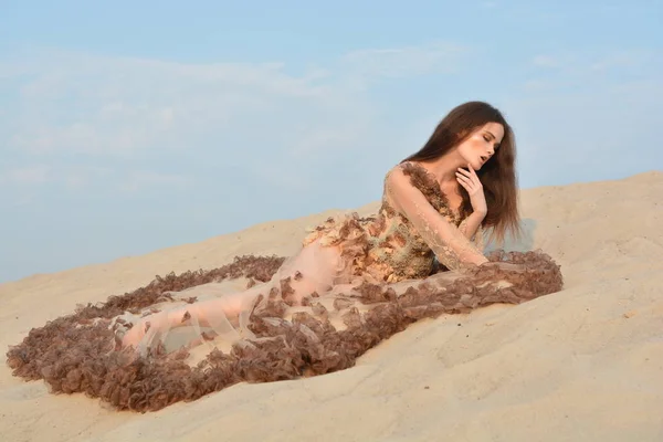 Fille attrayante qui se trouve sur le sable dans une robe de luxe avec un long train dans le désert — Photo
