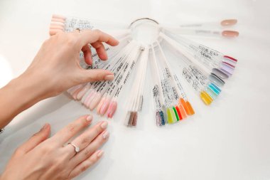 Bir kadın manikür salonunda oje rengini seçiyor, çıplak ve pembe renkler, renk paleti.