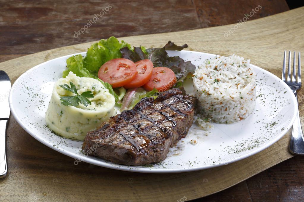 grilled steak with mashed potatoes, rice and vegetables