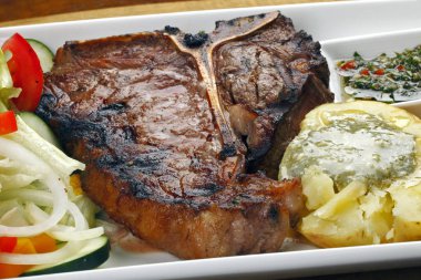 Kızarmış porterhouse veya t-bone biftek, patates ve salata ile ihale 