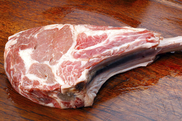 Raw Tomahawk Steak on wooden board