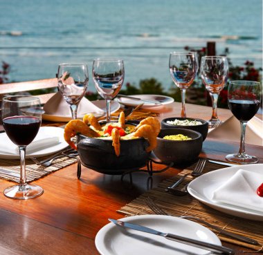 Arka planda deniz olan karides ve balık moqueca.