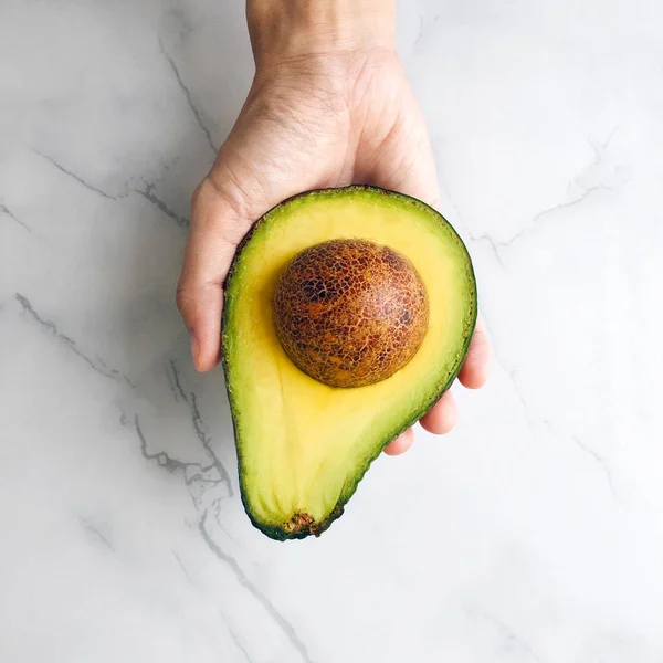 Holding half avocado — Stock Photo, Image