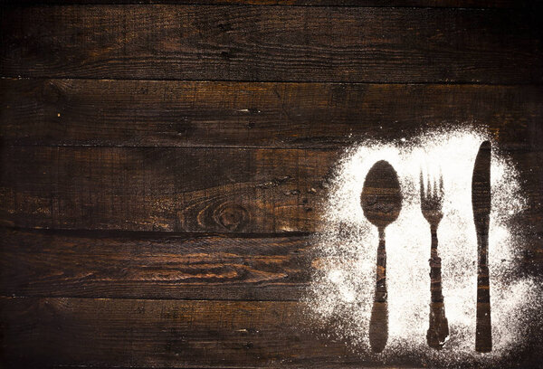 Контур столовых приборов на деревянном фоне

