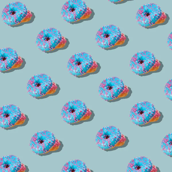 在柔和的蓝色背景上的蓝色釉面甜甜圈模式。创造性的概念. — 图库照片