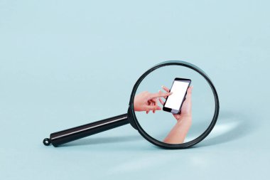 Bir akıllı telefon kullanan bir kişinin elleri üzerinde odaklanan bir büyüteç.