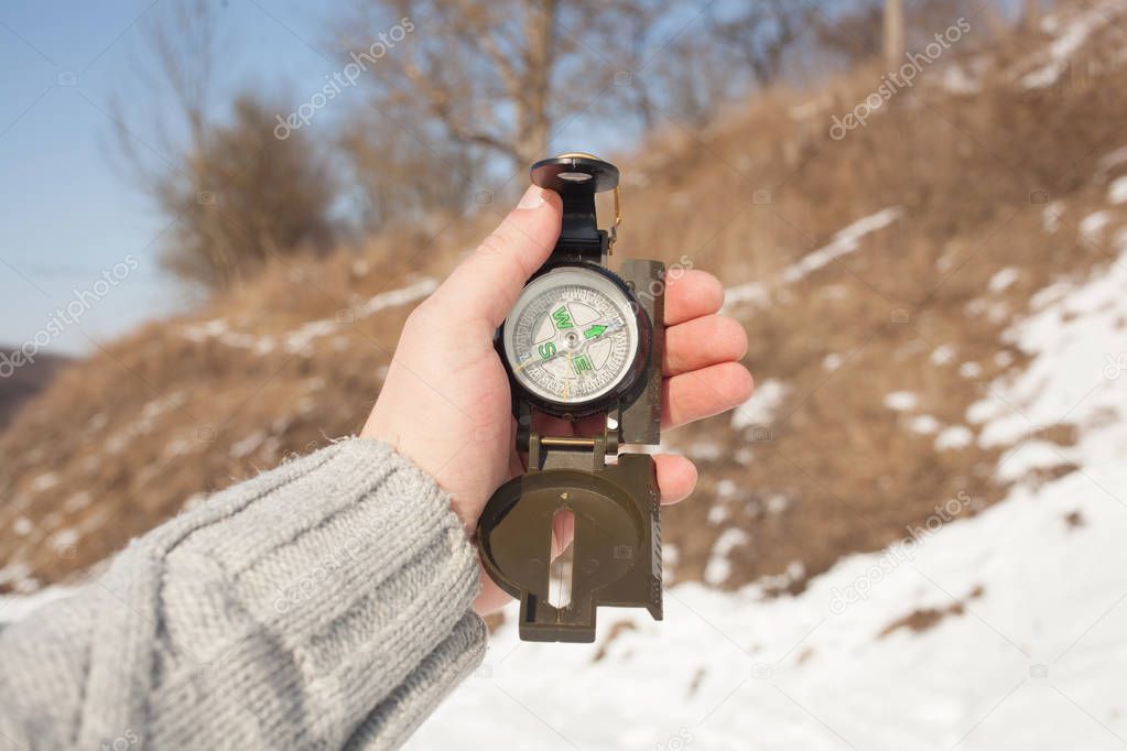 Hand holding a compass, winter time idea, searching direction.