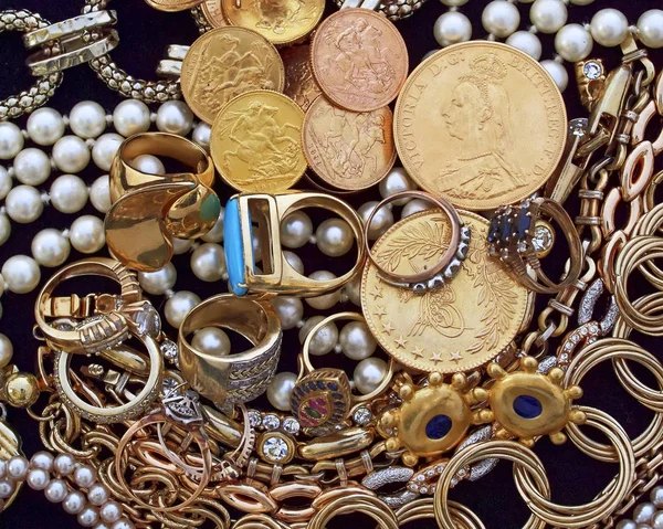 a collection of golden jewels and coins on black velvet background