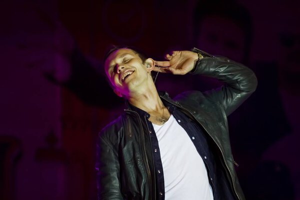 Концертное фото фронтмена известной всемирно известной латвийской рок-группы "Brainstorm" Ренарса Кауперса, делающего знак, что слушает кого-то
