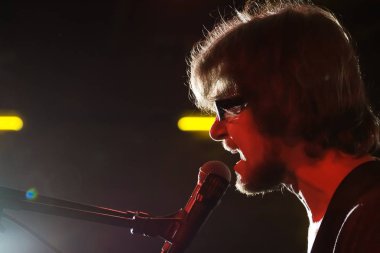 bir erkek şarkıcı Stas bir arka ışık Royal barda, Vinnytsia, 11.07.2013 karanlık bir arka plan üzerine bir şarkı performans Korolyov silüeti