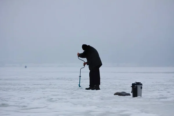 渔民在小的 自然的 冰冻的冬季湖上的形象 用手工制作冰洞 穿着保暖衣服的人物形象 装有渔具的塑料盒 冬季户外活动的业余爱好形象 — 图库照片