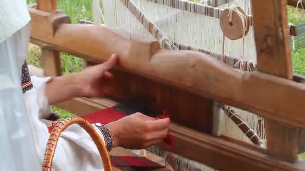 Manos de una hábil artista artesana que trabaja en telares antiguos, tejiendo alfombras en Live Fire Midsummer Pagan Ethno festival, arte tradicional — Vídeos de Stock