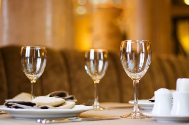 Şarap bardakları, tabaklar ve peçeteler zengin bir restoranda verilen akşam yemeği için hazır, sığ bir alan derinliği, bulanık bir arka plan.