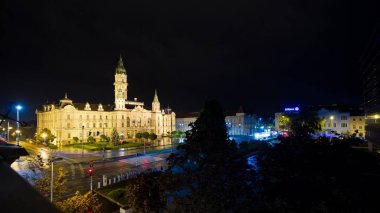 Gyor, Macaristan - 04.05.2019: yağmurdan sonra karanlık bir gecede belediye binası ve meydan, yoldaki araba ışıkları bulanık, Raba Şehir Merkezi 'nden uzun pozlu görüntü, turizm kartpostalı