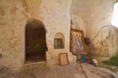 Lyadova, Ukraine - 09.06.2019: inside entrance to ancient monk caves cut in coquina cliff of Beheading of John the Baptist Rock Friary, icons left after holiday prayer ceremony
