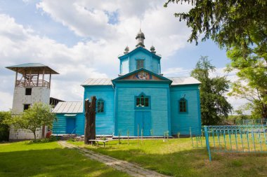 Prybuzke, Ukraine - 24.05.2019: Assumption of the Holy Mother of God russian Orthodox church, east side of temple, entrance and bell tower in a yard, religious faith concept