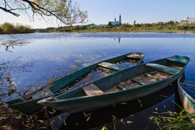 Eski püskü, ahşap botlar giyerdi, nehir kıyısında söğüt ağacının gölgesinde yeşile boyanırdı, yaz sabahı manzarası, kırsal Avrupa köyü eko-turizm kavramı.