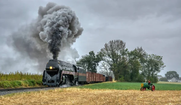 Norfolk és Western Steam mozdony No. 611 Tehervonat fúj a füst és a gőz, ahogy halad egy időszak Farm traktor vidéken — Stock Fotó