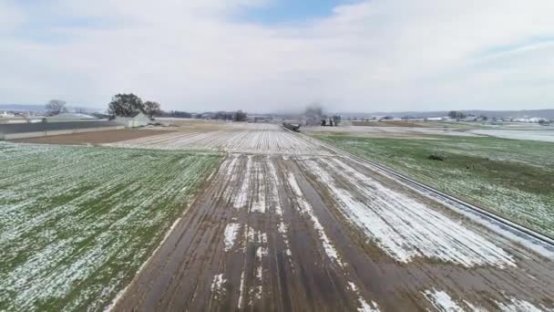 2018年11月ペンシルベニア州ストラスバーグ シーズン最初の雪の後にアミッシュ農場の土地に沿ってパフィン蒸気機関車と乗用車のアリエルビュー — ストック動画