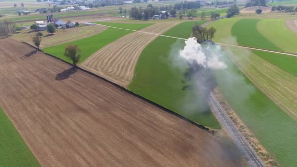 Vue aérienne d'une ancienne machine à vapeur restaurée voyageant à travers les terres agricoles soufflant de la fumée et de la vapeur dans mon chemin de drones 