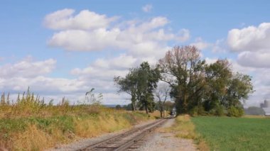Siyah duman üfleyen antika bir buhar makinesinin kırsal alanda yolcu vagonlarını çekişini izledik.