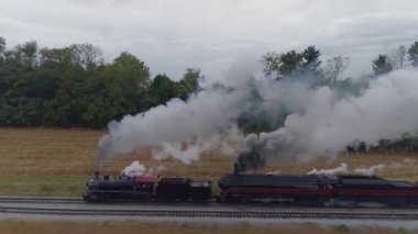 İki Buharlı Lokomotifin Hava Tarafı Görünümü Kara Duman ve Buharla Birlikte Bir Yük Treni Başlığı