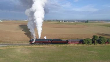 Strasburg, Pennsylvania, Ekim 2019 - Bir N & W buhar makinesinin yan yana havadan görünüşü kırsal alanda buhar üflemesi, tarım arazisi manzaralı yolcu vagonlarını çekmeye hazırlanıyor