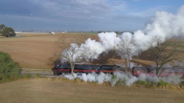 ペンシルベニア州ストラスバーグ2019年10月 W蒸気機関が蒸気と煙を吹いている様子を空中から眺めながら 晴れた日に農地を眺めながら乗用車を引く — ストック動画
