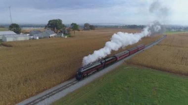 Strasburg, Pennsylvania, Ekim 2019 - Bir N & W buhar makinesinin hava açılı görüntüsü buhar ve duman püskürterek mısır tarlaları üzerinden yolcu vagonlarını çekiyor.